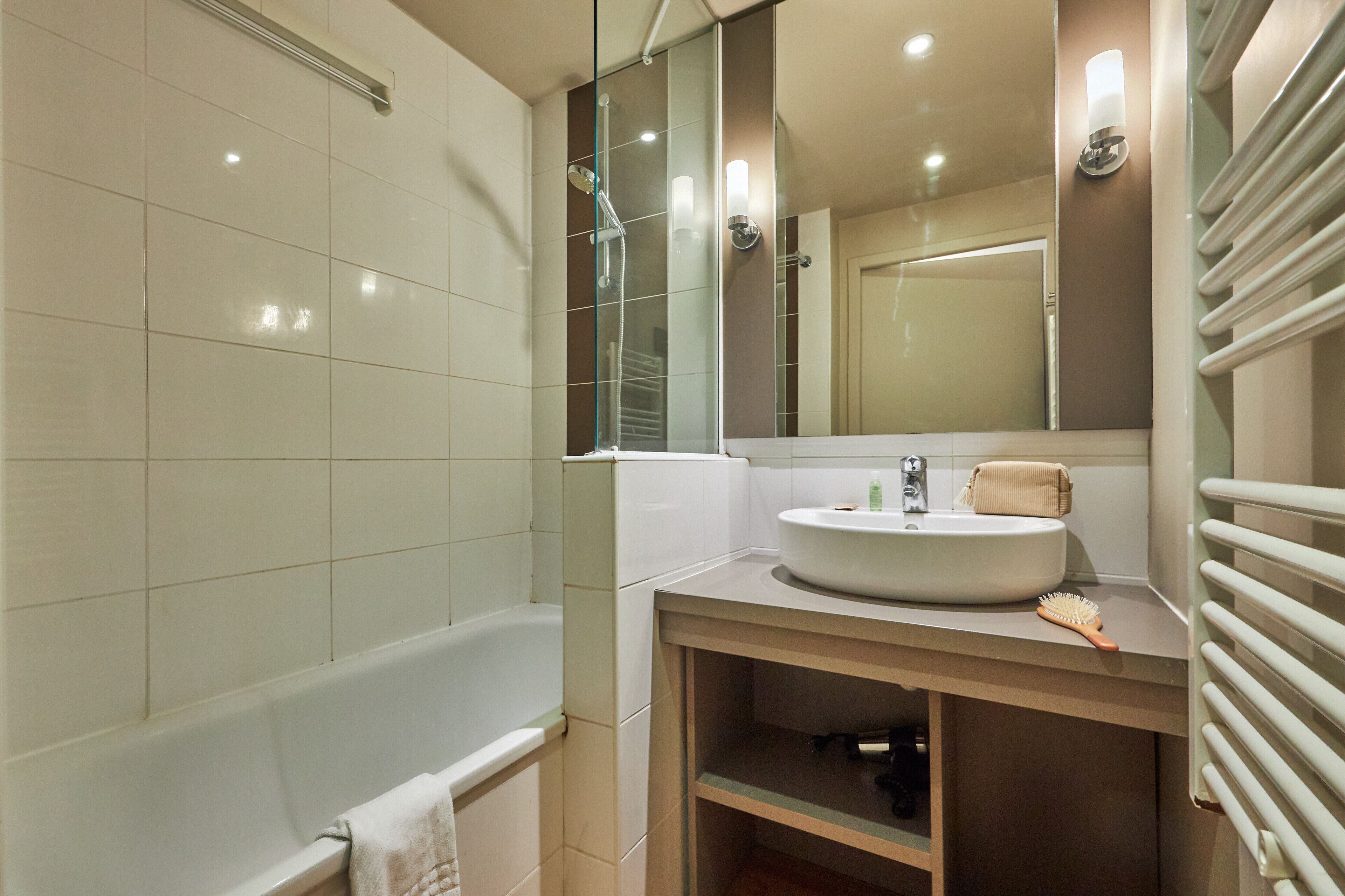 Un baño moderno con bañera, lavamanos, espejo y toallero.