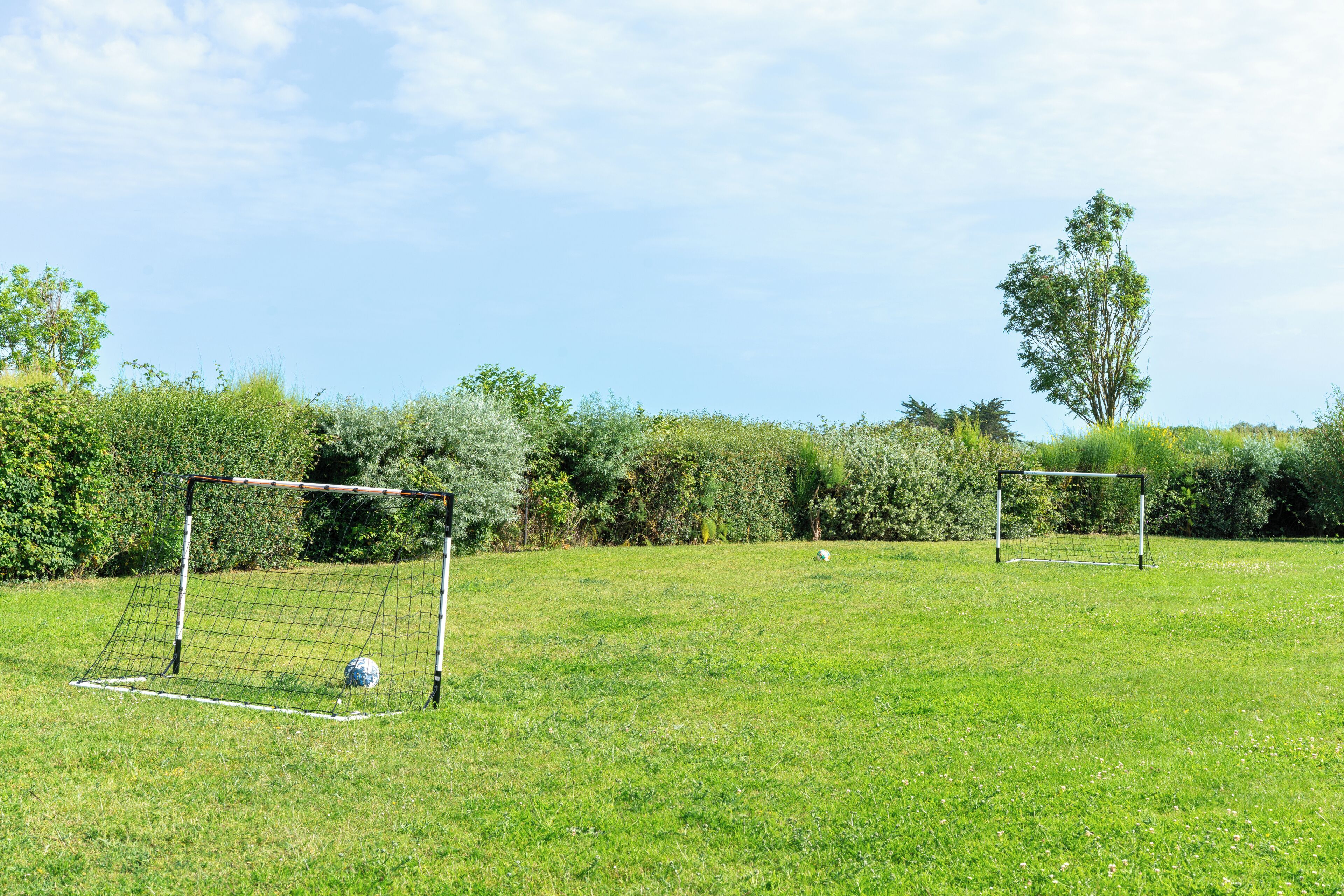 A soccer field with two goals and a ball.