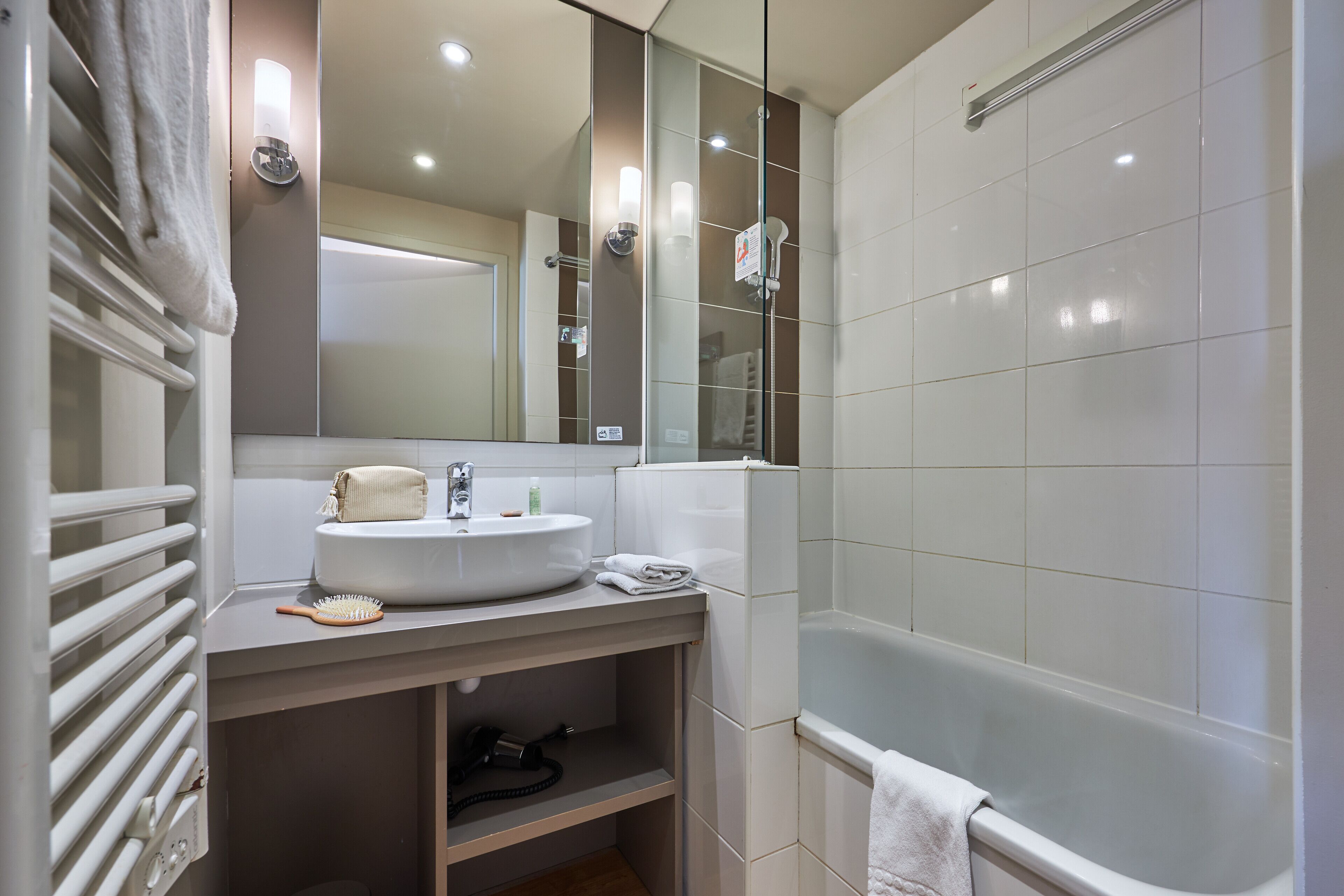 Un baño moderno con un lavabo blanco, espejo y bañera.