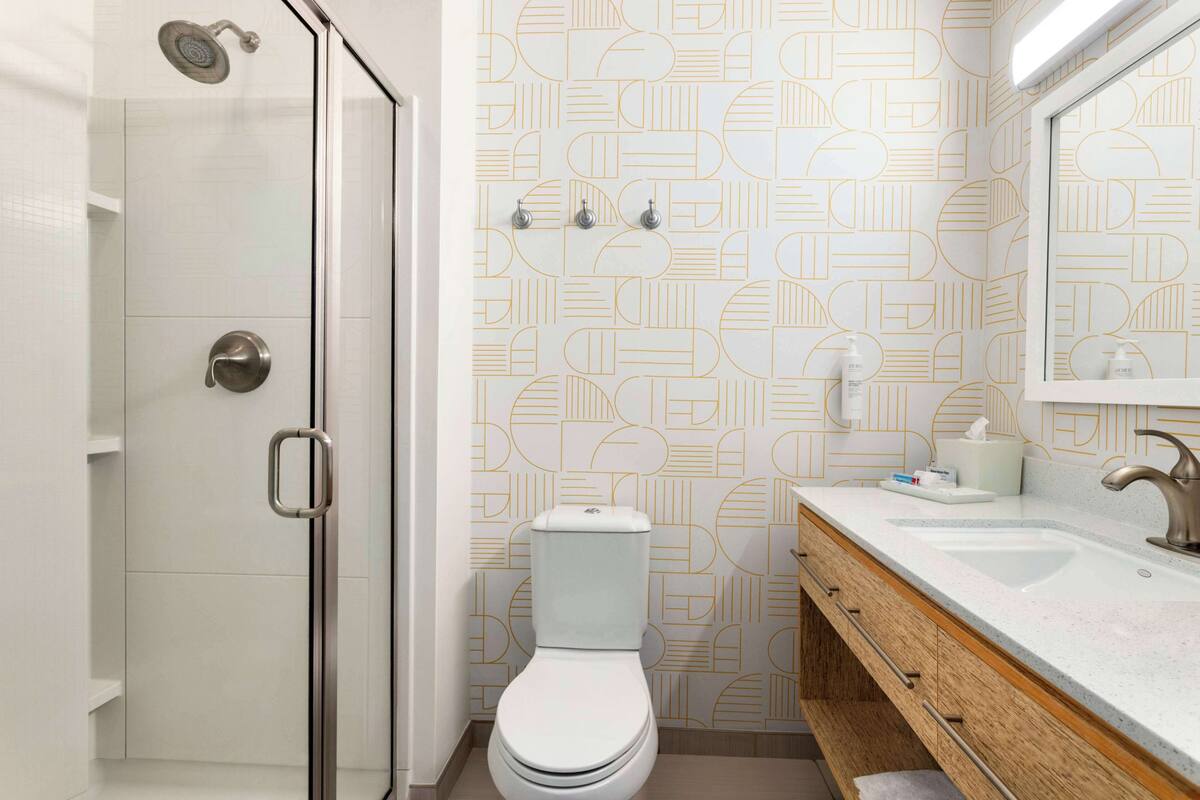 A bathroom with a shower, toilet, and vanity with a mirror.