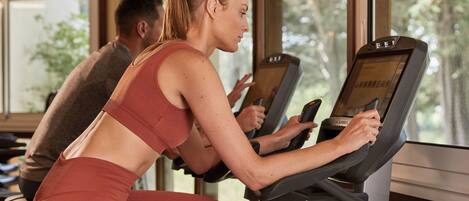 Un gimnasio con cintas de correr y un ventanal grande.
