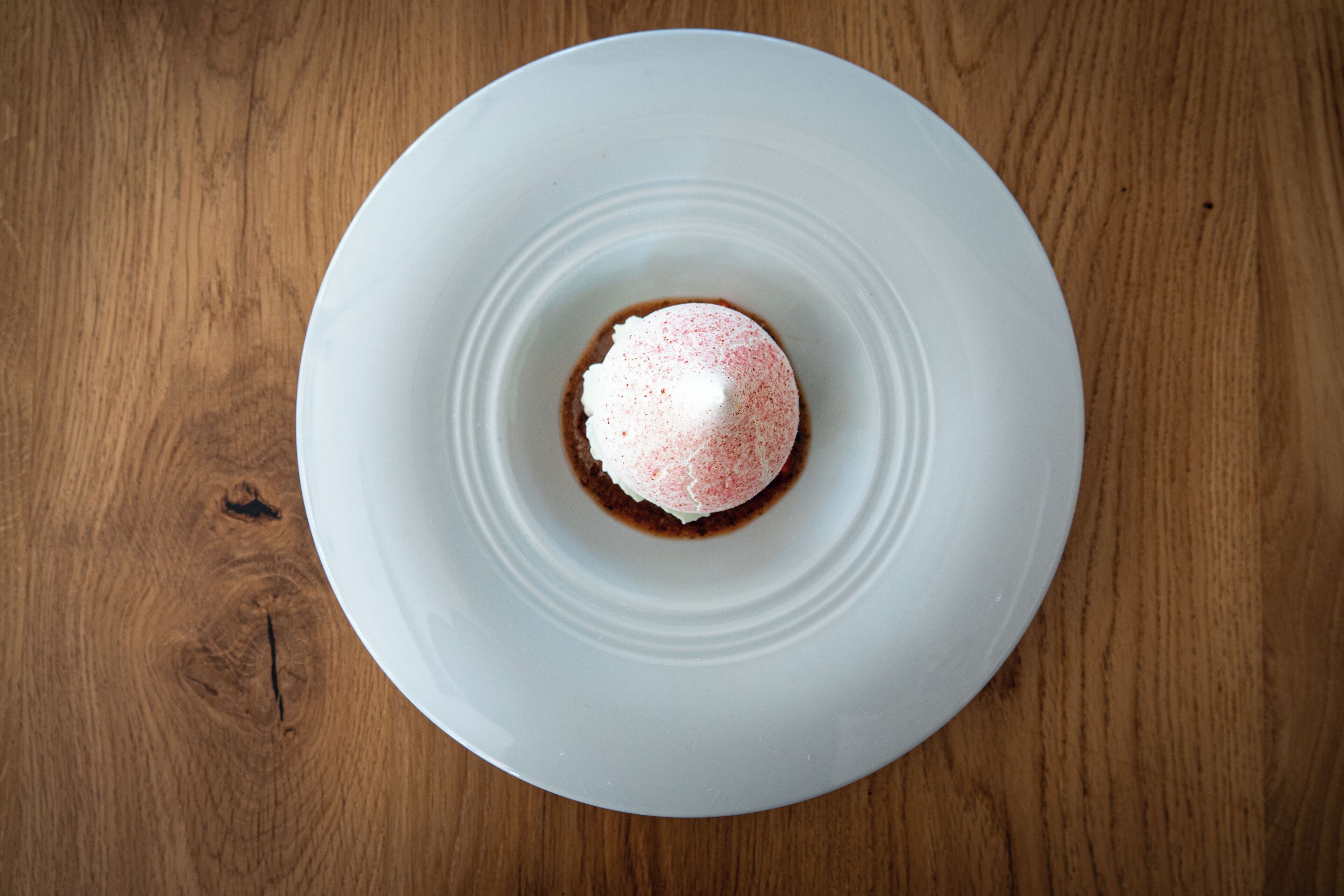 Un plato blanco con un postre sobre una mesa de madera.