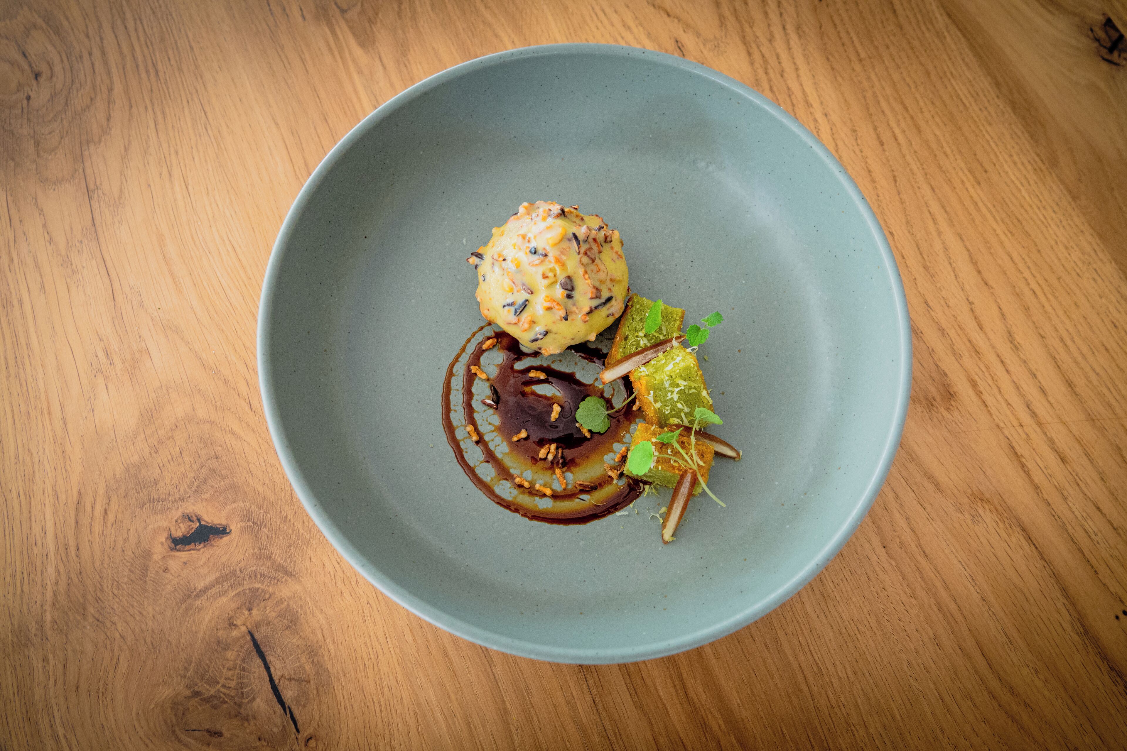 A round, light blue ceramic plate with a dessert on a wooden table.