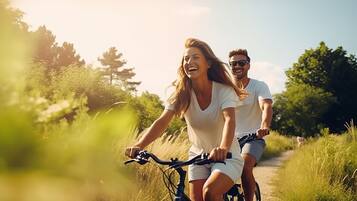 Dos personas montando en bicicleta por un sendero iluminado por el sol, rodeado de follaje.