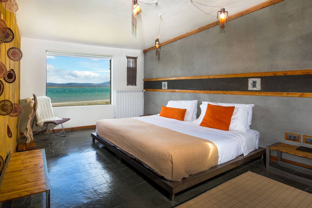 Una habitación de hotel moderna con una cama grande, vista al mar y suelo de madera.