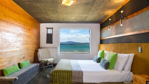 Une chambre moderne avec un grand lit, une vue sur la mer et un banc en bois.