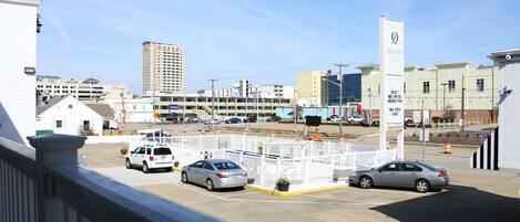 A parking lot with several cars, a white fence, and buildings in the background.