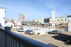 A parking lot with several cars, a white fence, and buildings in the background. - Oceans 2700 (Virginia Beach)