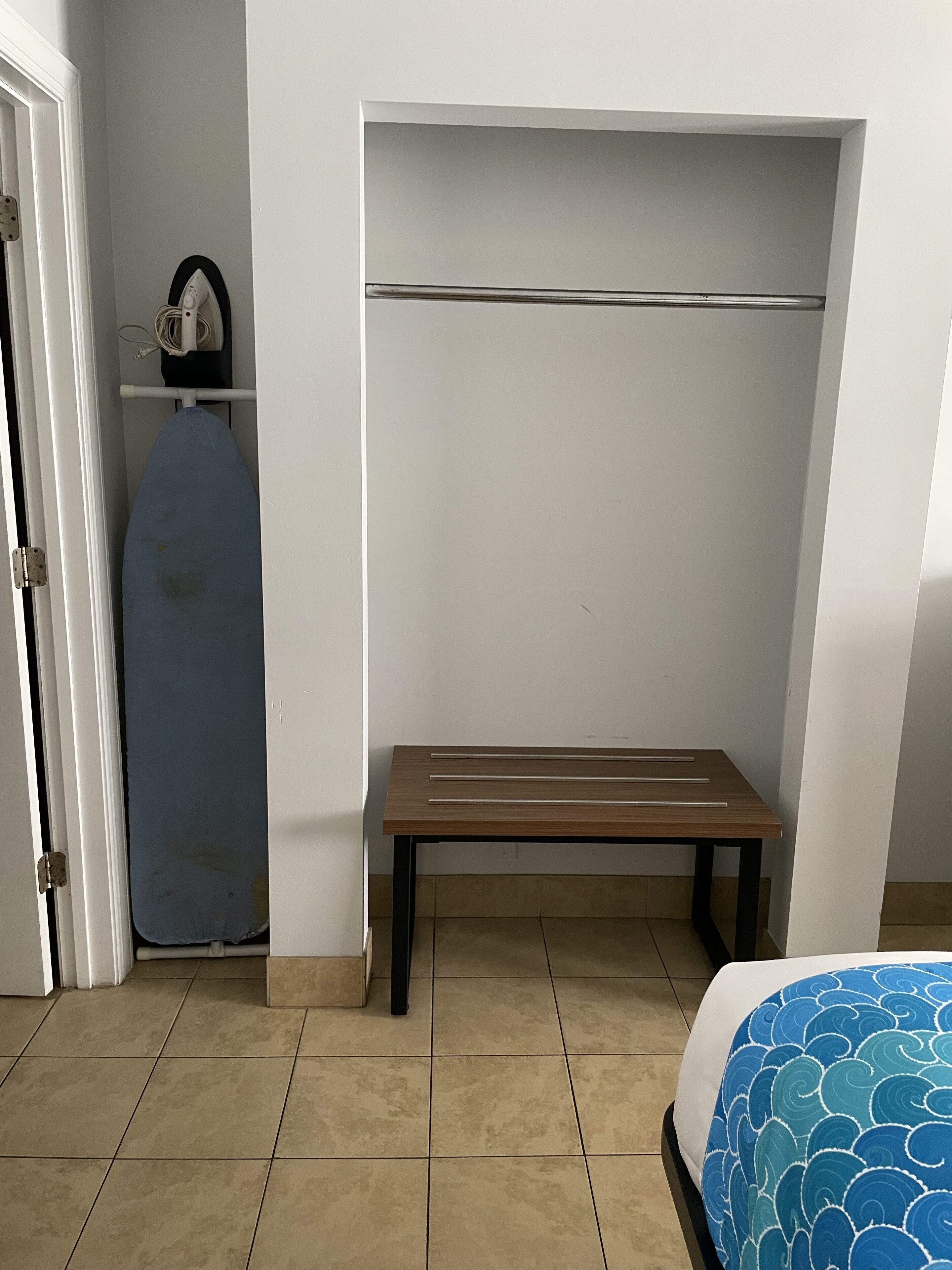A bedroom with a bed, a bench, a wardrobe, and a door.