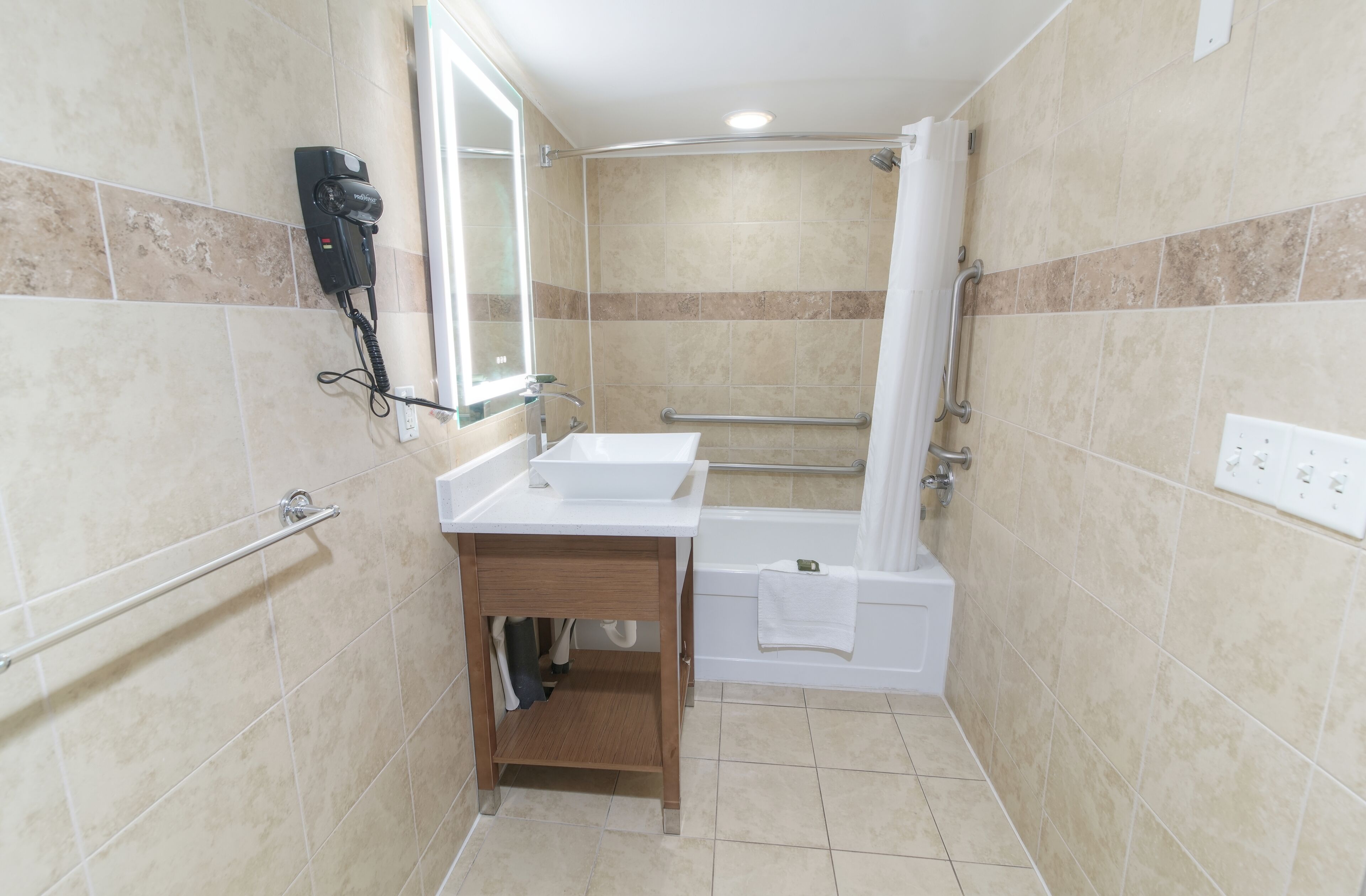 A small bathroom with a sink, mirror, and shower.