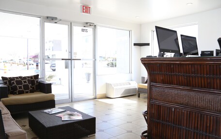 A lobby with a sofa, a coffee table, a fireplace, and a reception desk with computers.