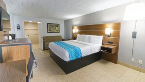 Habitación de hotel con cama, mesita de noche, escritorio, silla y puerta de baño.