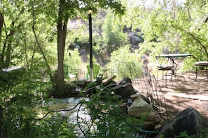 Un cadre extérieur paisible, avec un petit ruisseau, des tables de pique-nique et une clôture en métal.
