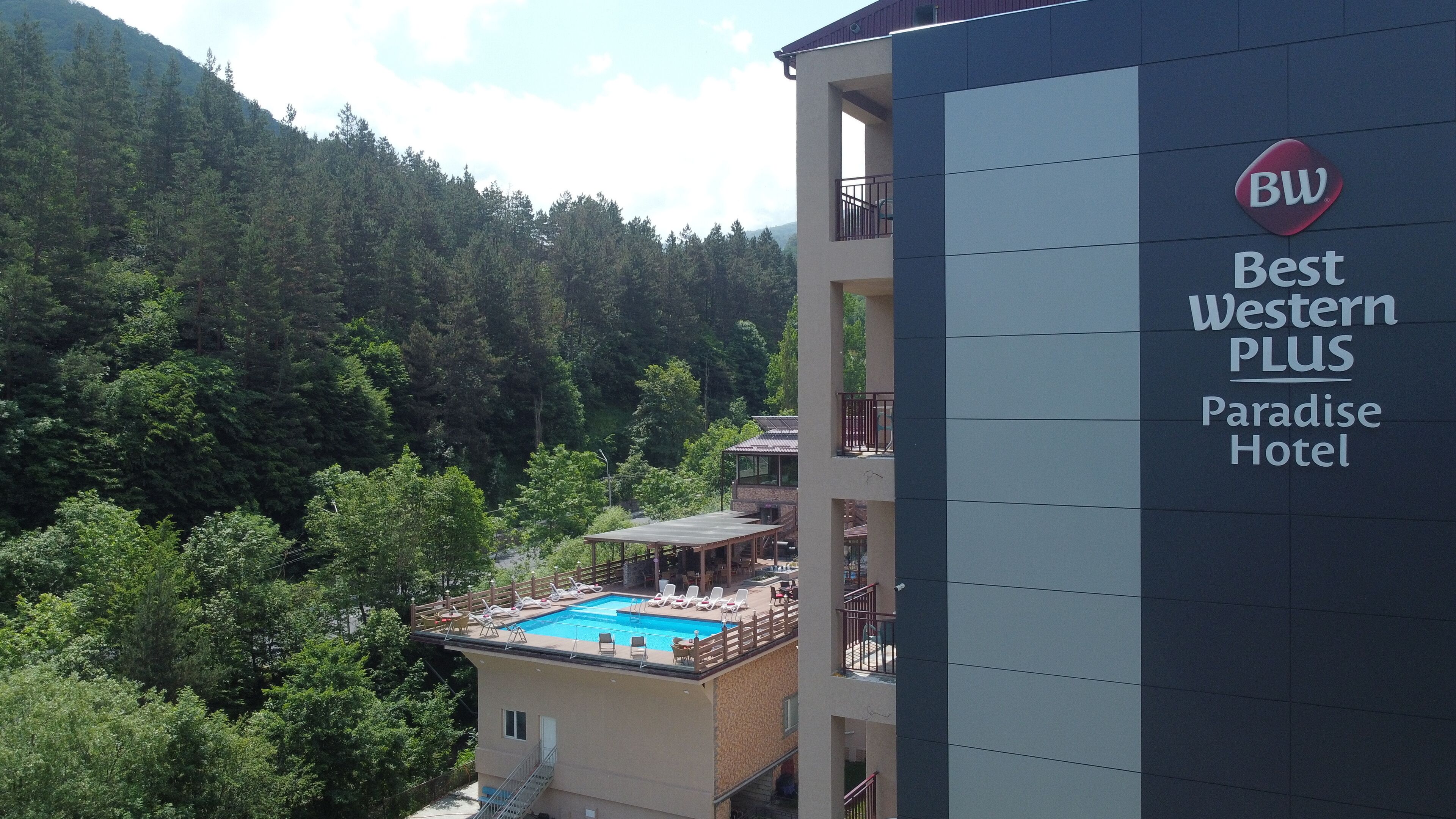 Un hôtel doté d’une piscine sur le toit, entouré d’une végétation luxuriante et de montagnes.