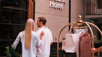 Een stel staat voor een gebouw met een bord waarop 'Best Western PLUS Paradise Hotel' staat.