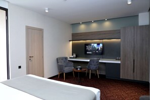 A hotel room with a bed, a desk with two chairs, a television, and a wardrobe. - Best Western Plus Paradise Hotel Dilijan (Dilijan)