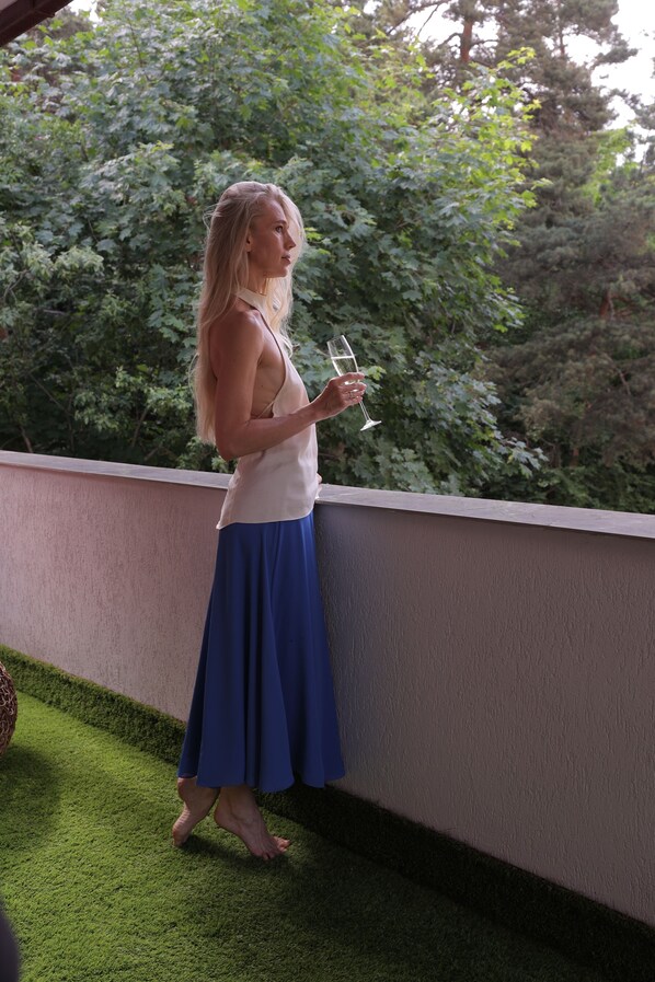 A person standing on a balcony with a view of greenery.