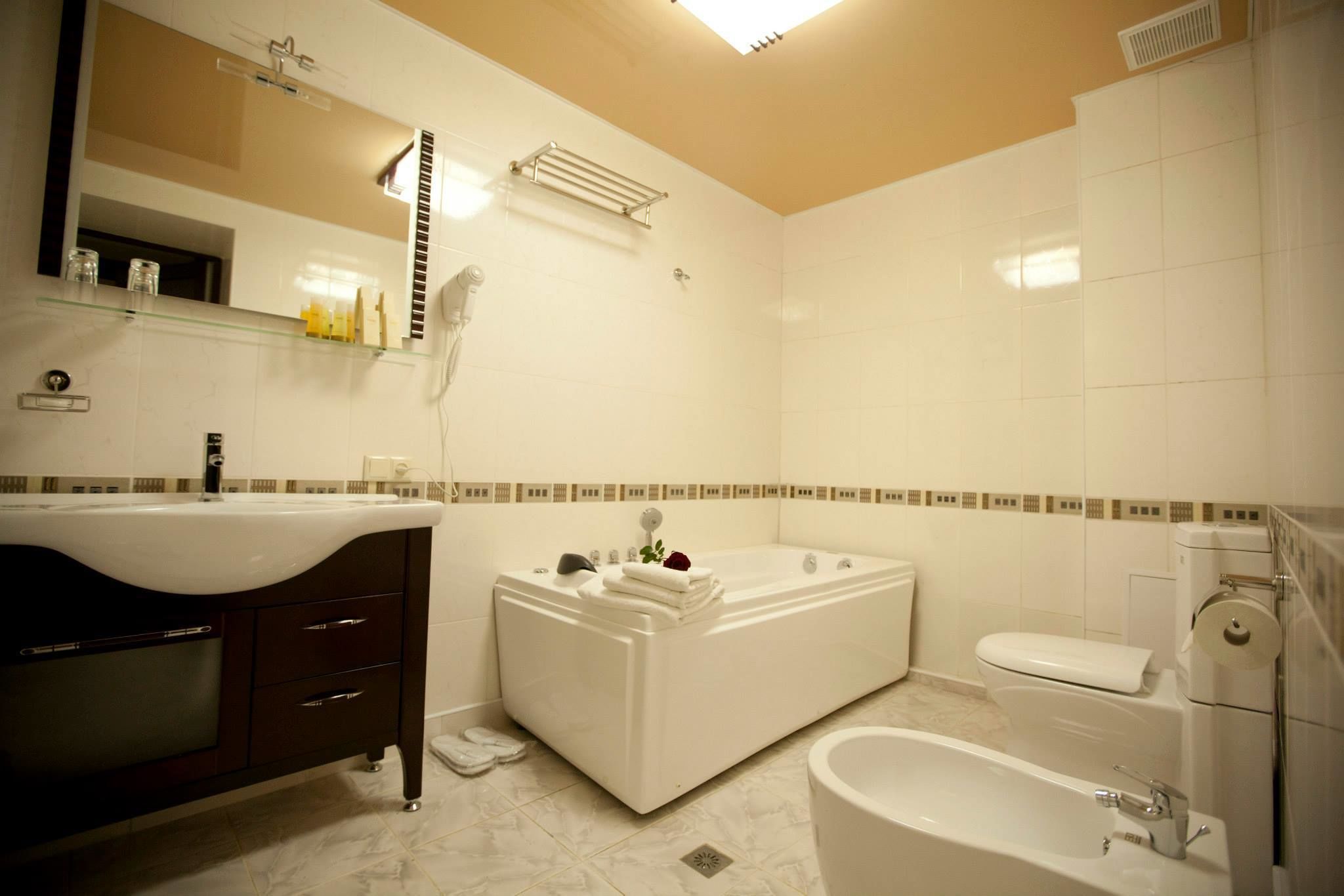 Un baño con una bañera grande, un inodoro separado y un tocador con cajones.