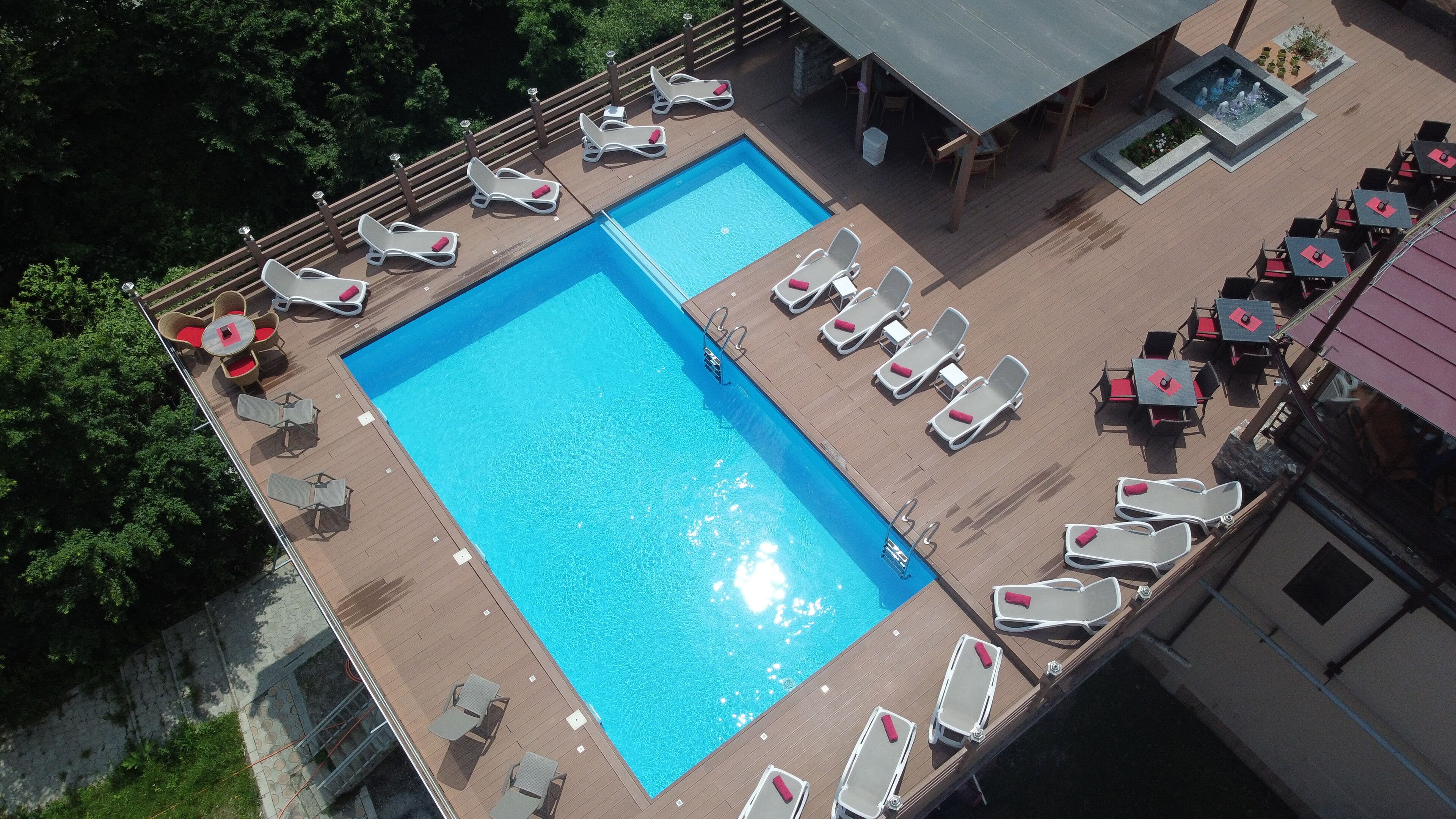 Piscina en la azotea con múltiples tumbonas y una zona de estar techada.