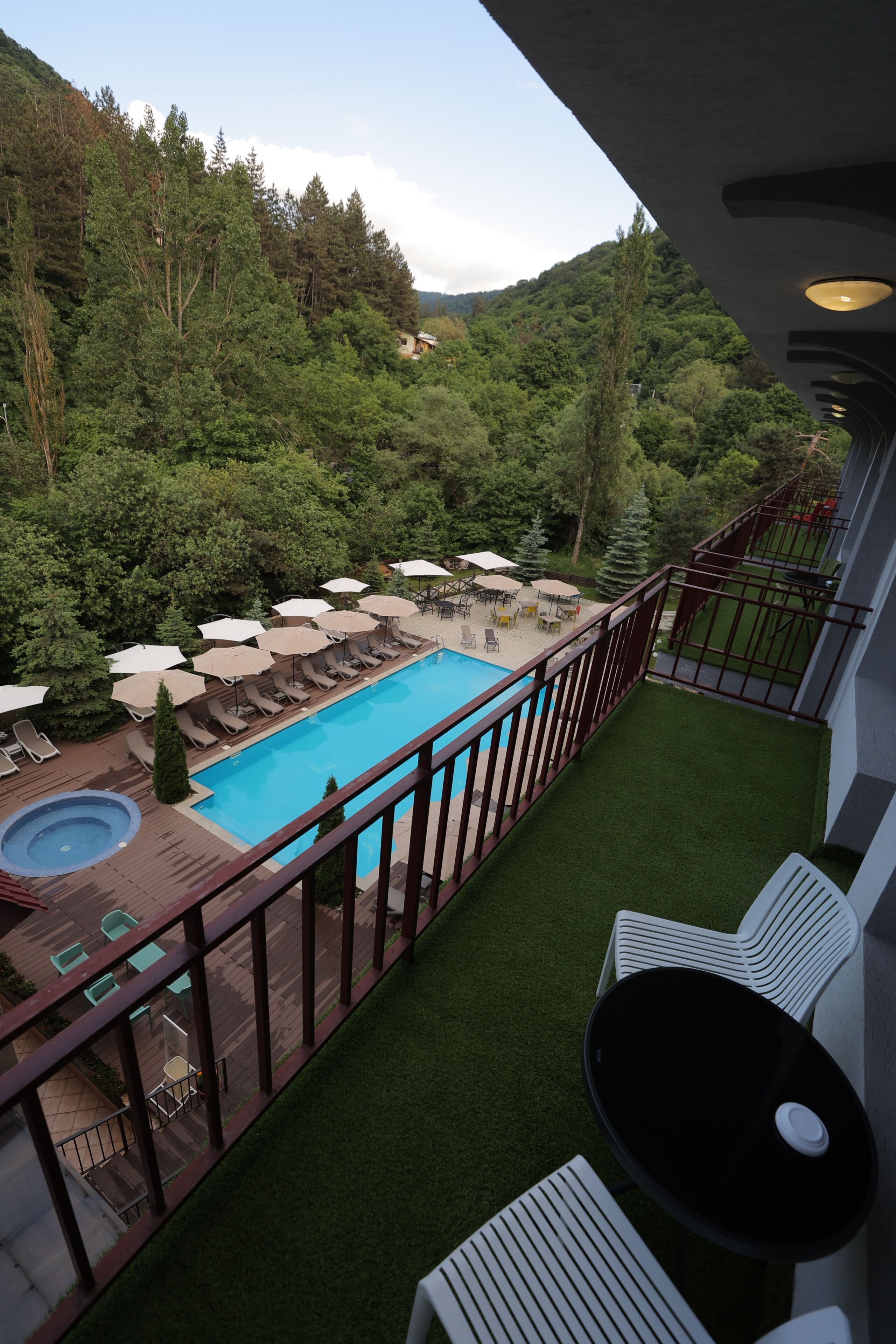 Un balcon avec une piscine, des chaises longues et une vue sur une zone boisée.