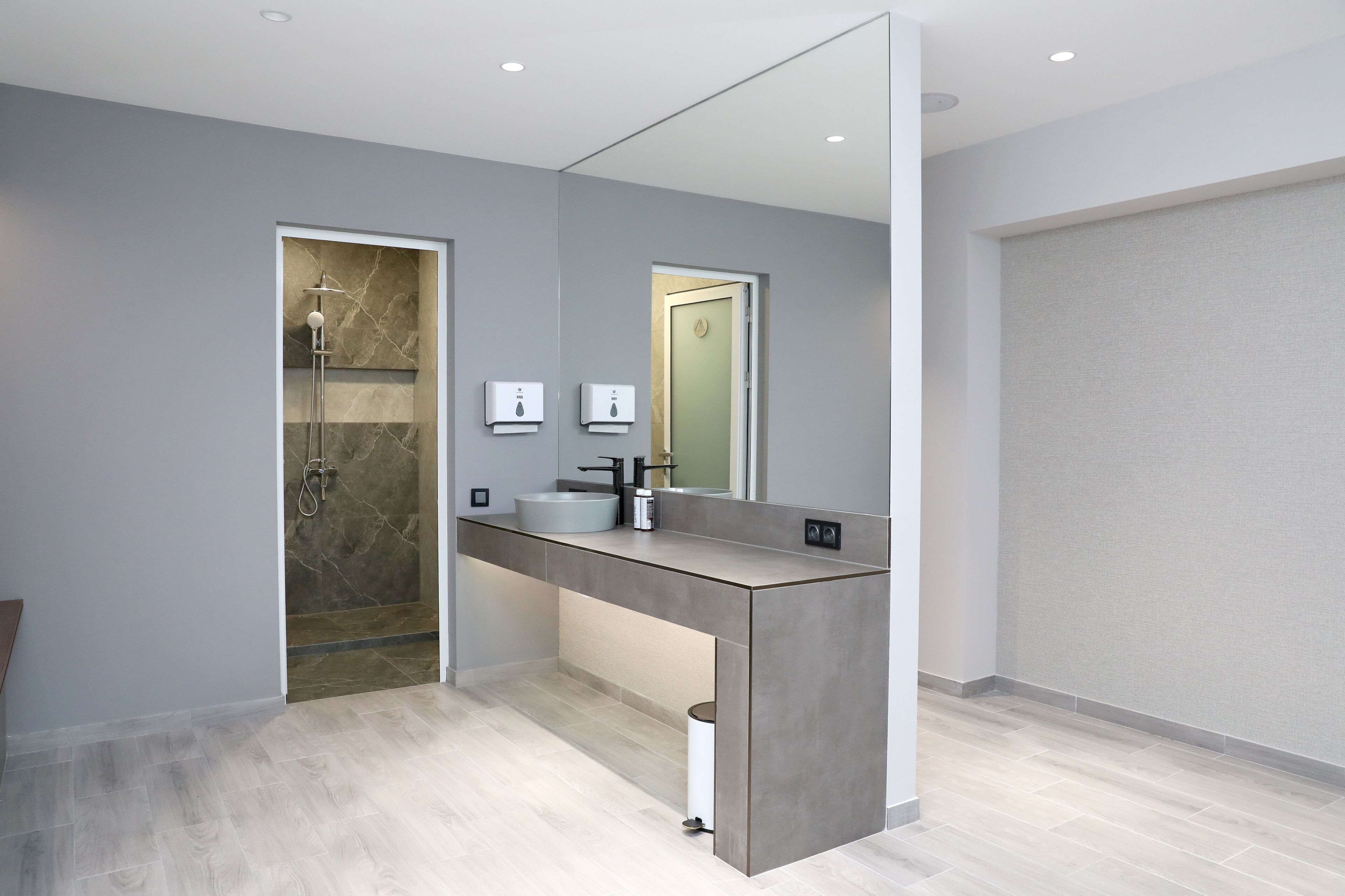 Une salle de bain moderne avec un grand miroir, un lavabo intégré et une cabine de douche.