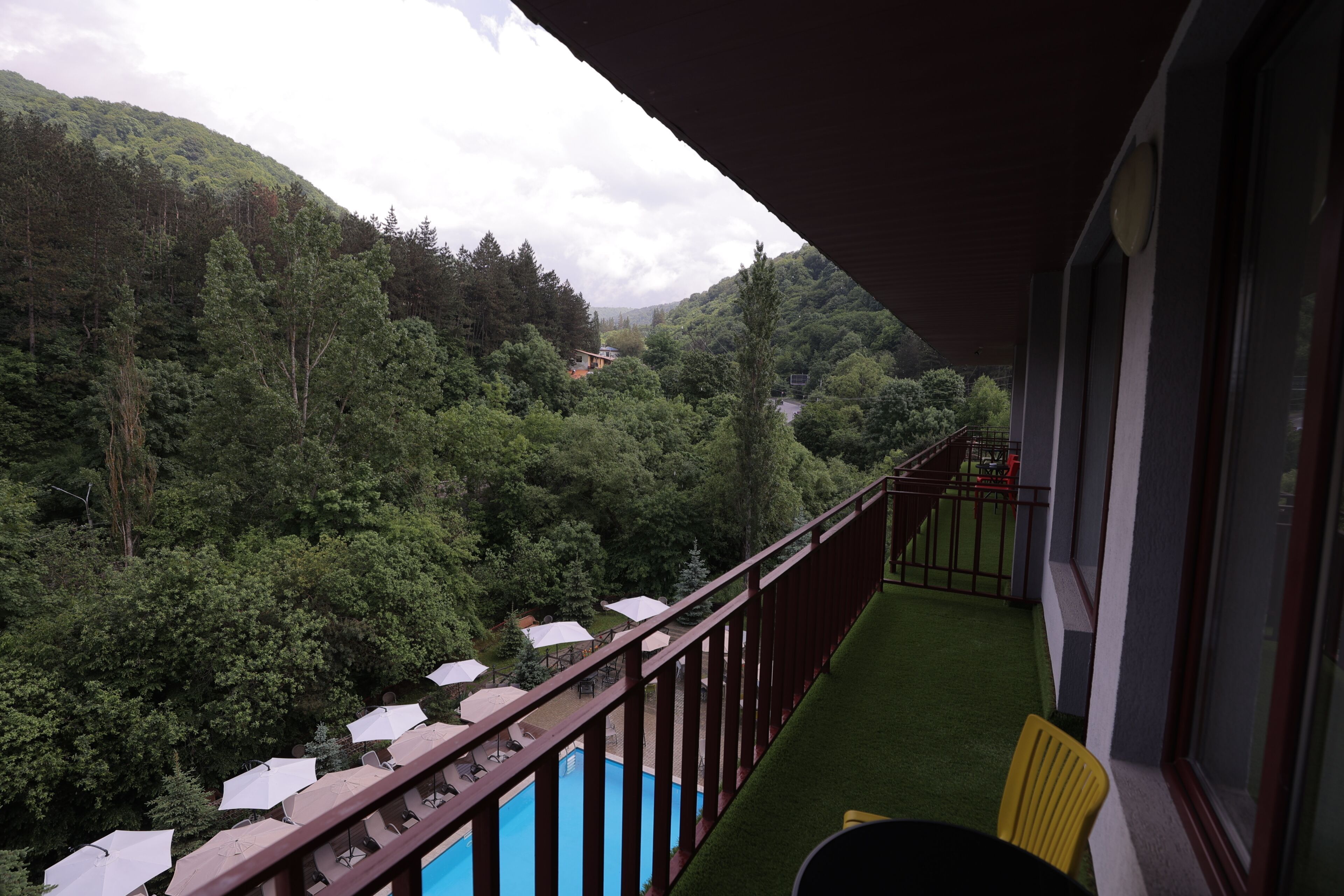 Un balcone con piscina, immerso nel verde e con vista sulle montagne.