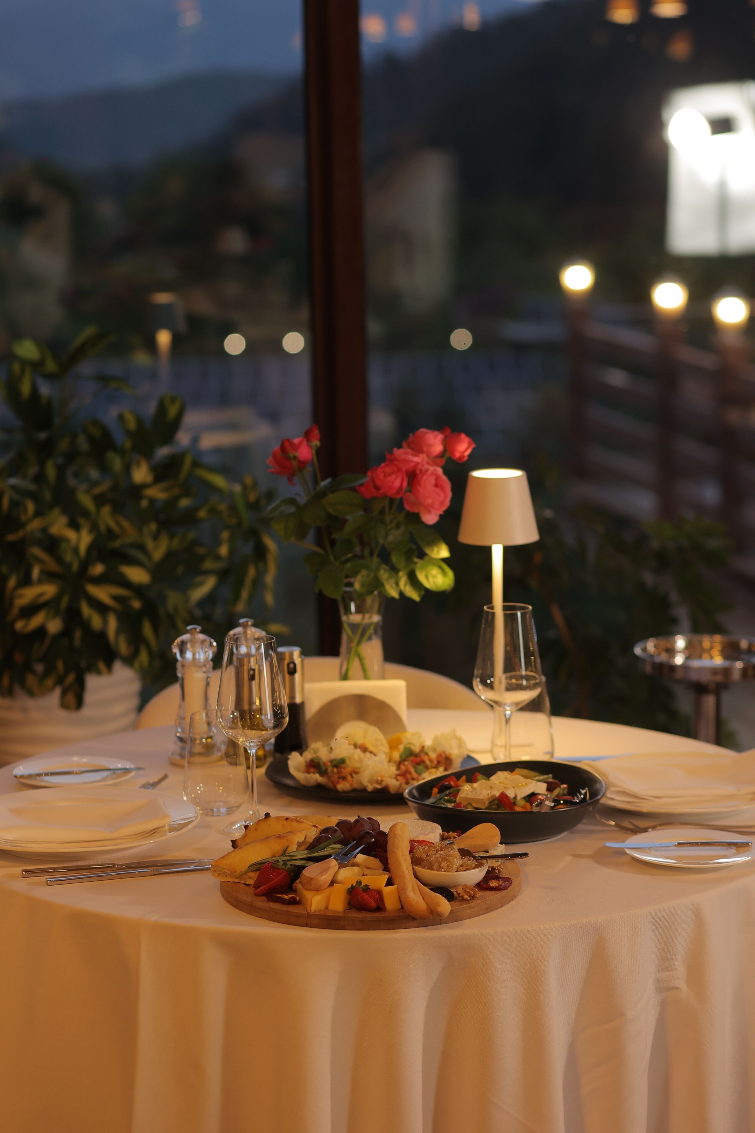 A table set for a meal with a view of the city at dusk.