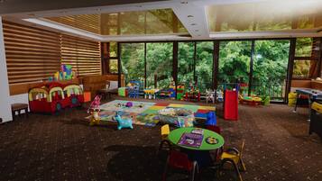 A spacious children's playroom with large windows, a variety of play structures, and a carpeted floor.