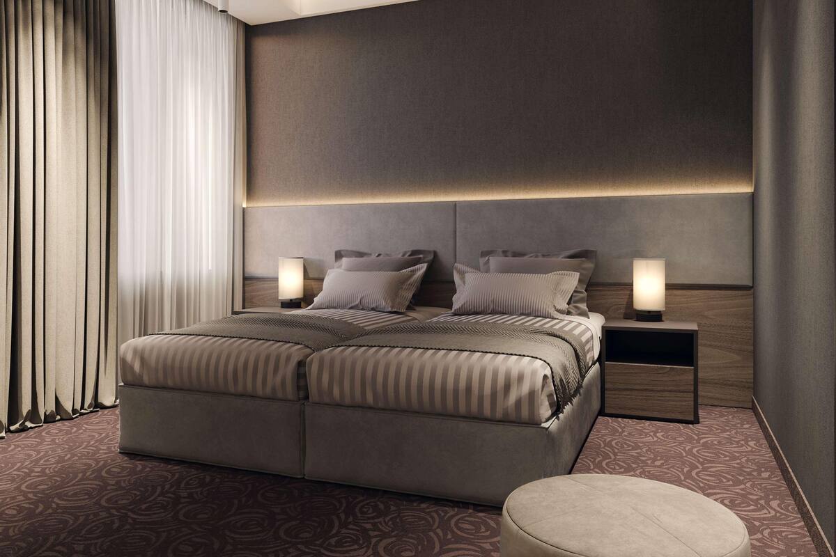Ein modernes Hotelzimmer mit einem großen Bett, zwei Nachttischen und einem Kopfteil mit integrierter Beleuchtung.