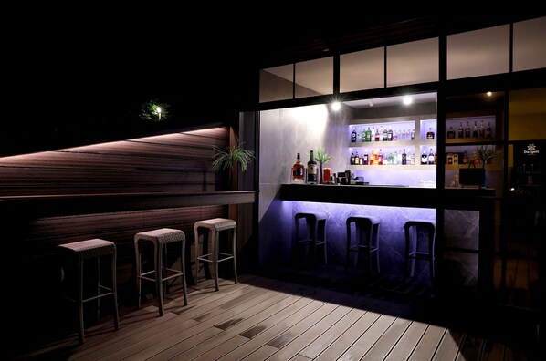 A bar area with wooden flooring, bar stools, and a well-lit shelf displaying various bottles. - Best Western Plus Paradise Hotel Dilijan (Dilijan)