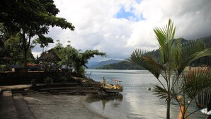 Une plage avec un petit bateau, une construction à toit de chaume et des palmiers.