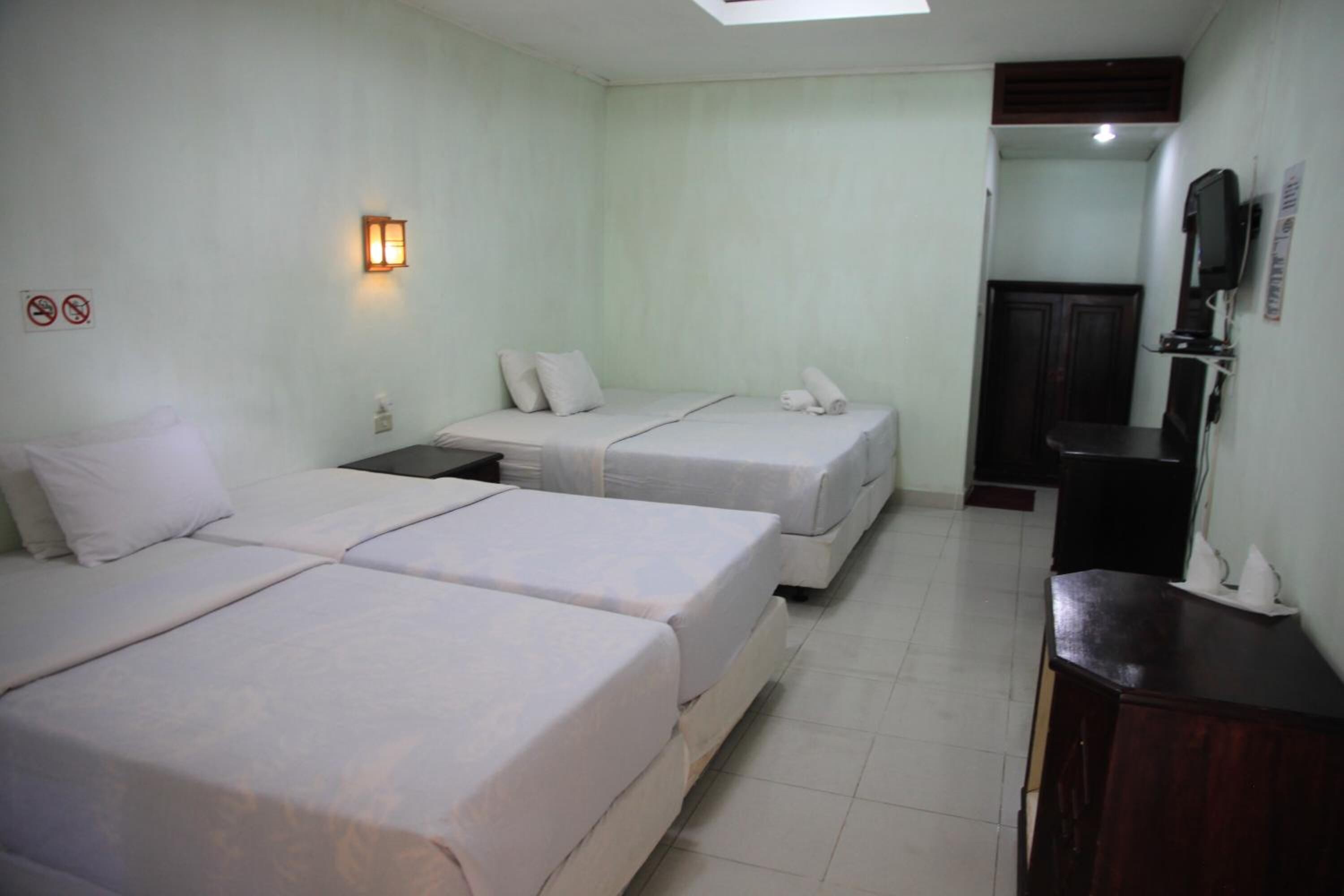 A hotel room with two beds, a desk, a TV, and a bathroom door.