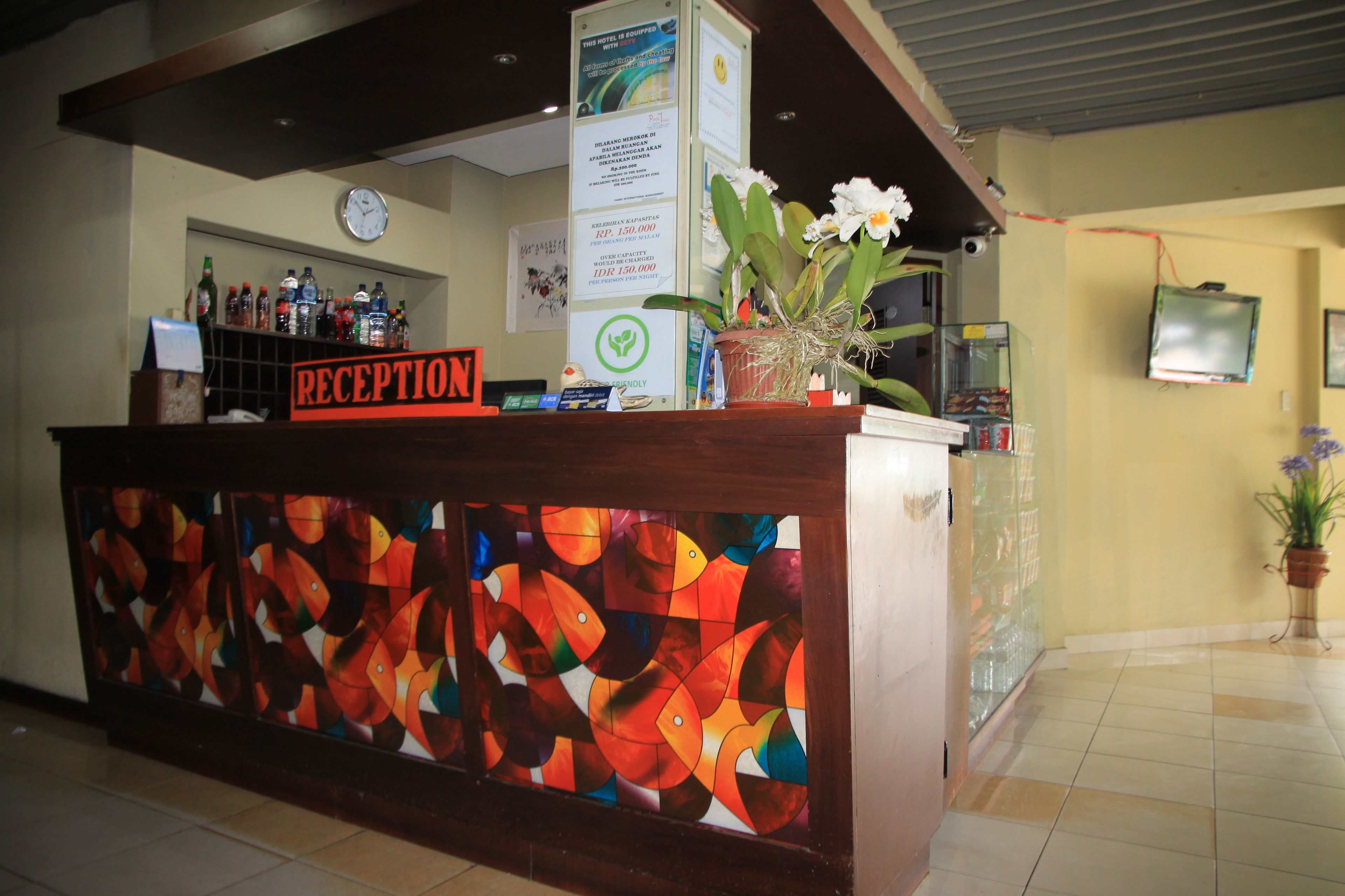 A reception desk with a colorful abstract artwork, a clock, and a potted plant.
