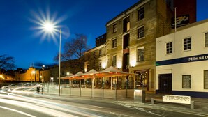 A street scene at dusk with a restaurant and a building with a sign that reads "Mission". - Customs House Hotel (Hobart)
