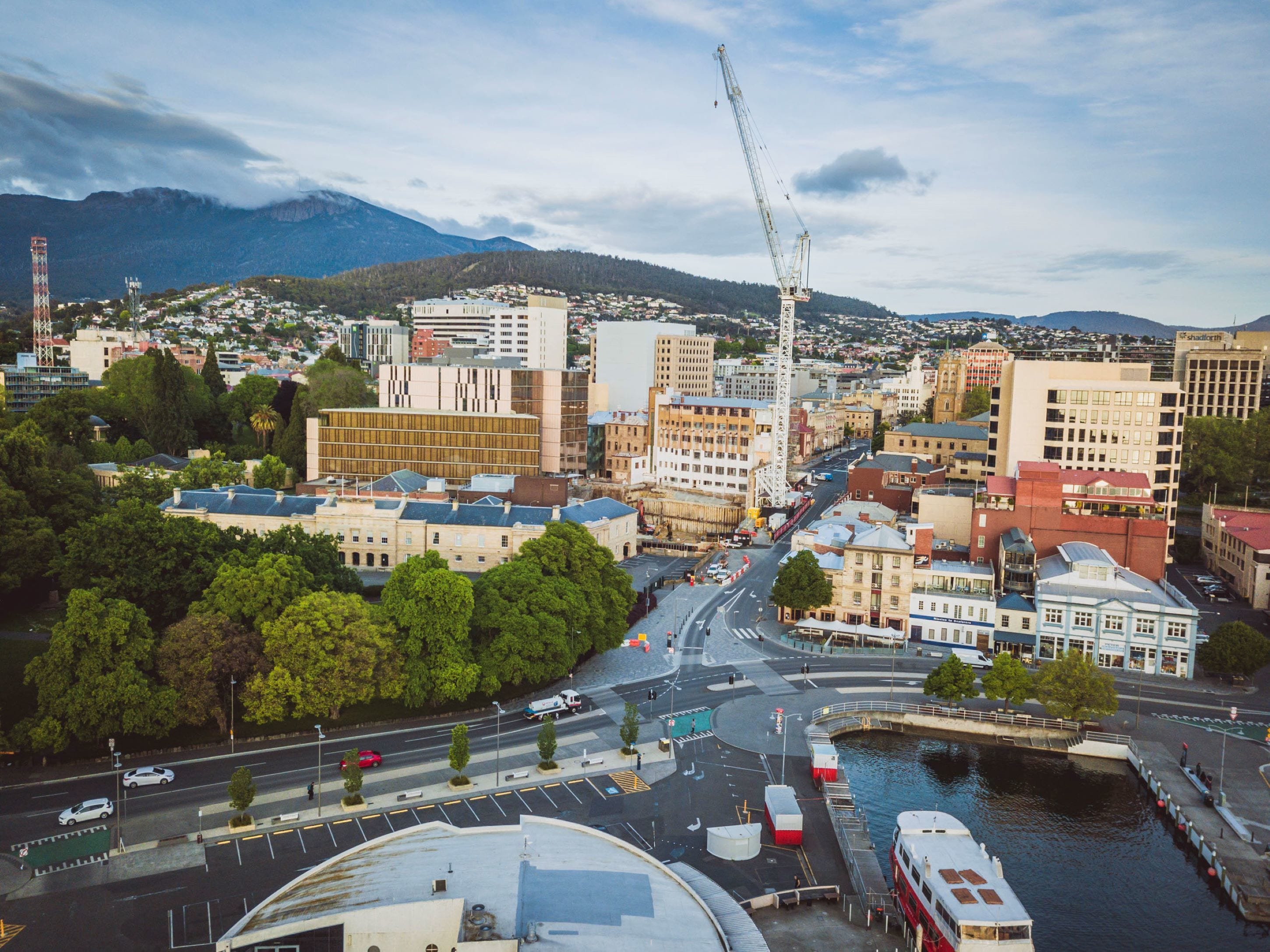 A cityscape with a river, buildings, and a construction crane.