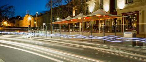A street at night with a building featuring a restaurant.