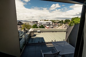 Un balcón con una mesa y una silla, con vistas a un paisaje urbano con edificios y un río.