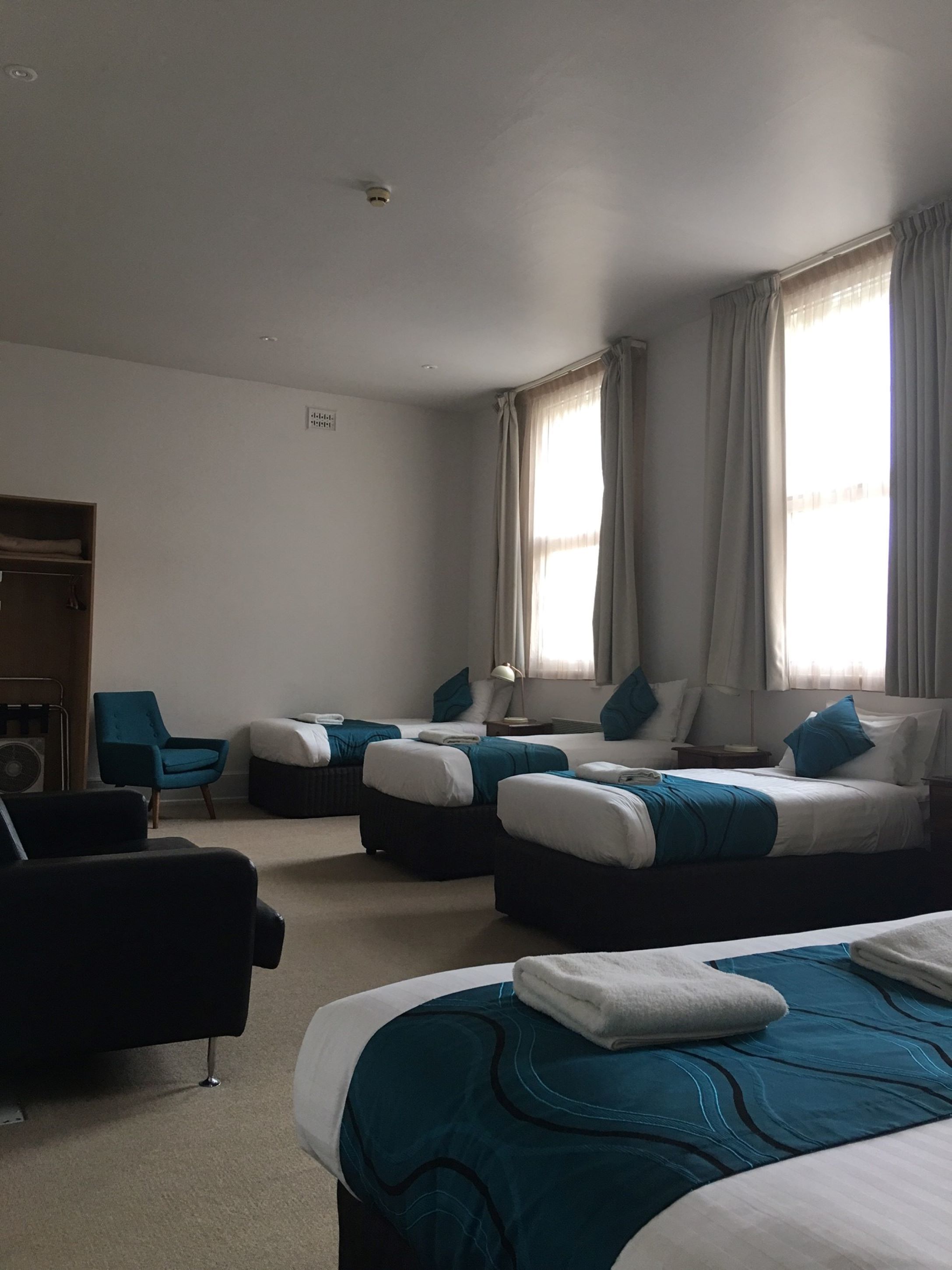 A hotel room with two beds, a sofa, a chair, and a small table.