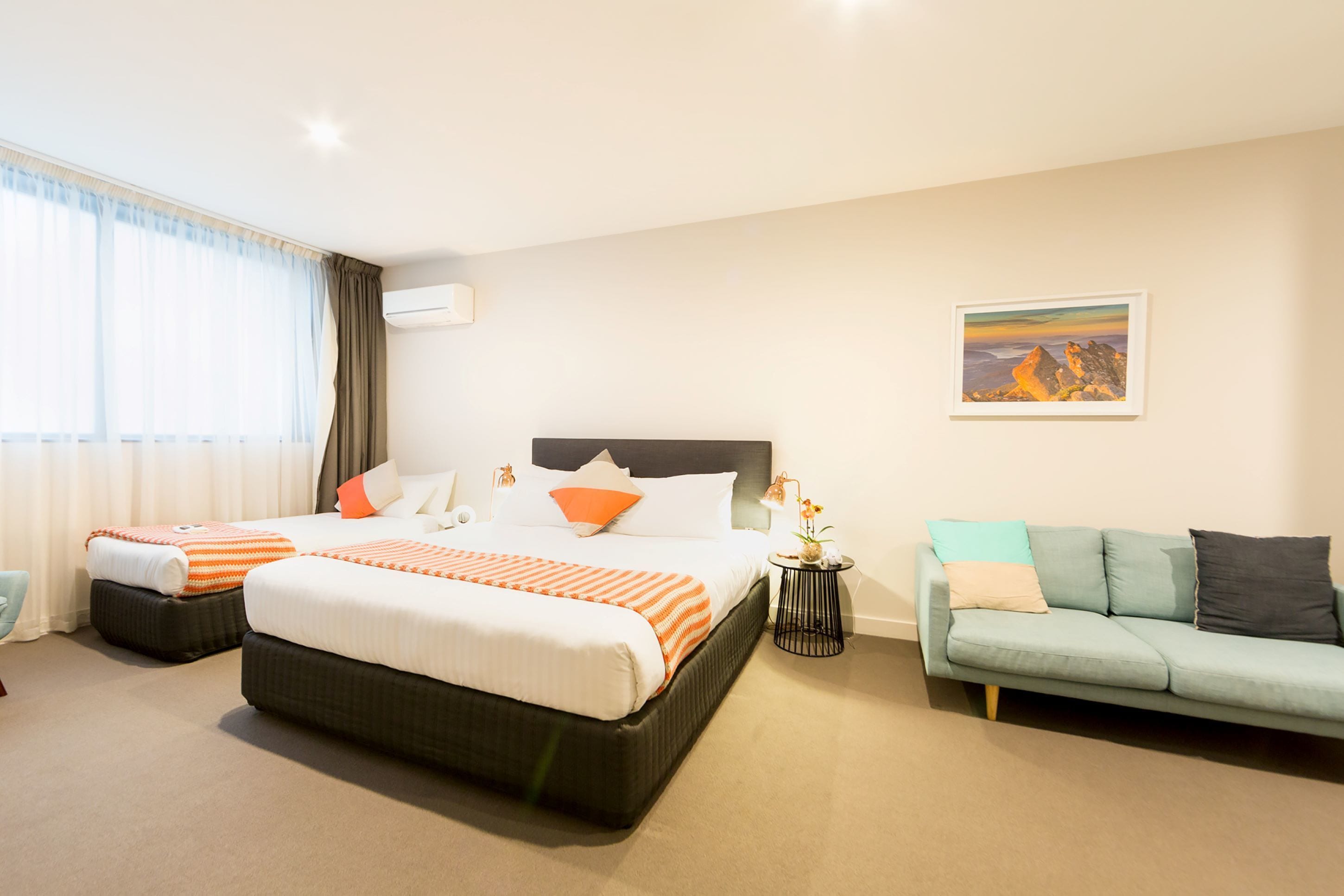 Een hotelkamer met een groot bed, een bank, een tafeltje met een lamp en een schilderij aan de muur.