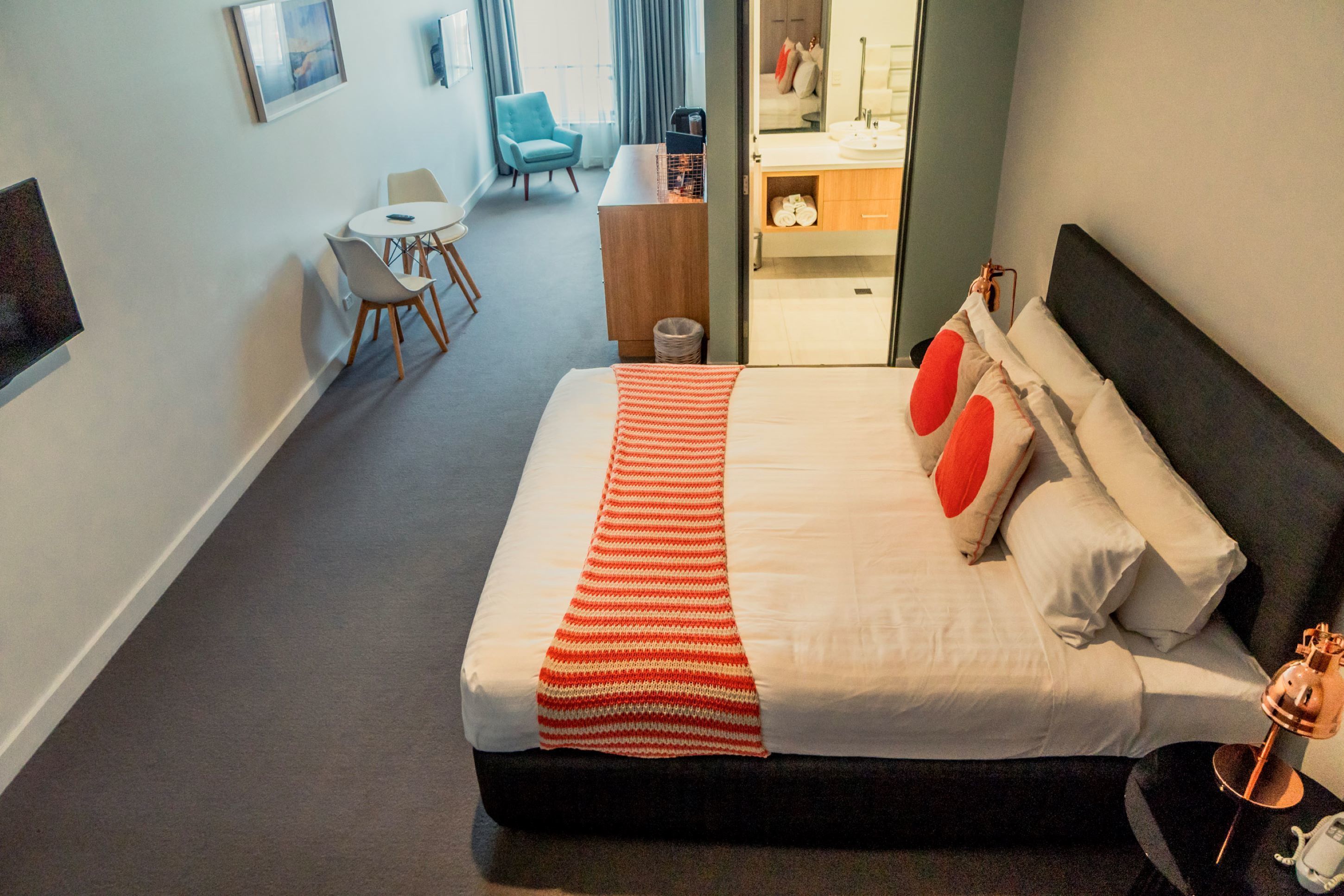 Una habitación de hotel con una cama grande, un escritorio, una silla y una mesita.