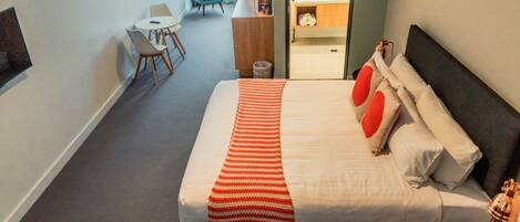 Una habitación de hotel con una cama grande, un escritorio, una silla y una mesita.