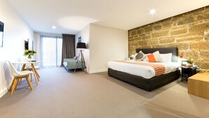 A modern hotel room with a large bed, a desk, and a dining area. - Customs House Hotel (Hobart)