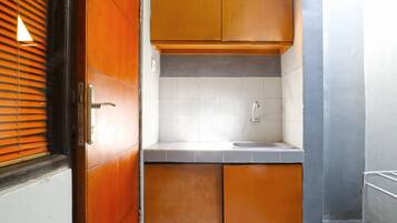 Una cocina compacta con armarios de madera, un salpicadero de azulejos blancos y un fregadero de acero inoxidable.