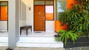 A modern building entrance with a wooden door marked '10', a bench, and a potted plant. - Sayang Residence 2 (Denpasar)