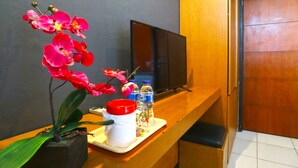 A reception desk with a potted orchid, a white mug, and bottled water. - Sayang Residence 2 (Denpasar)