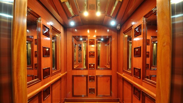 A wooden elevator interior with polished floors and brass handrails. - Jun Yue Hotel (Phnom Penh)