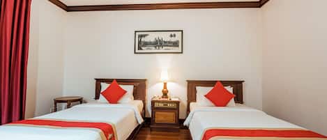 Habitación de hotel con dos camas, una mesita de noche con lámpara y un cuadro en la pared.