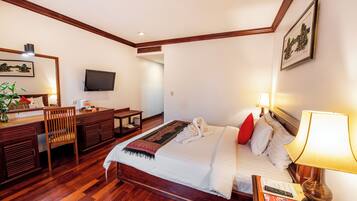 Une chambre d’hôtel avec un lit, un bureau, une chaise et un téléviseur fixé au mur.