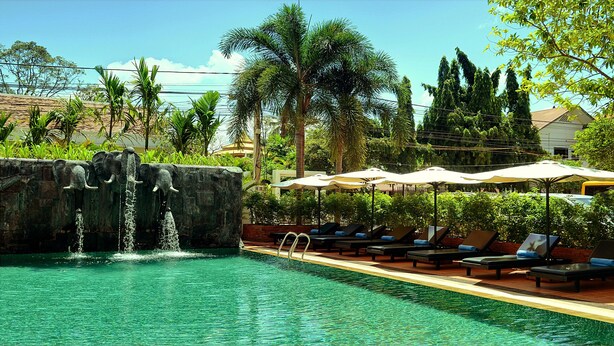 Un área de piscina con cascada, sillas de descanso y sombrillas.