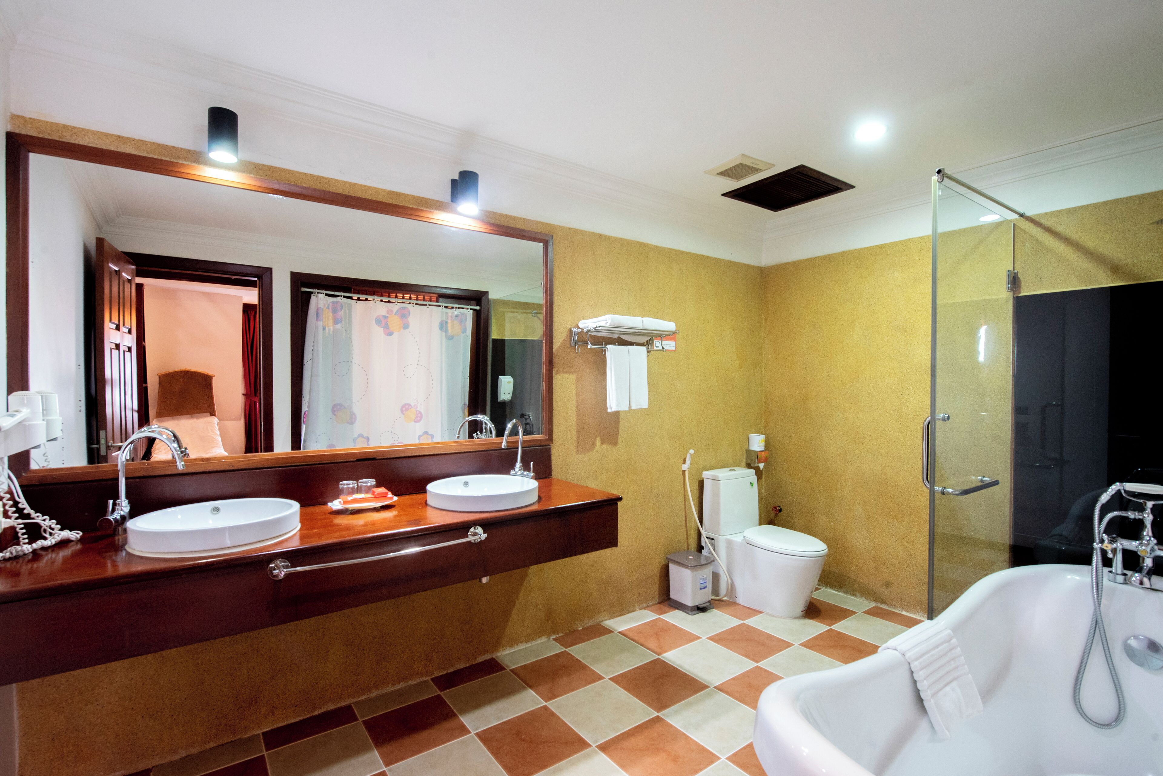 Ein Badezimmer mit großem Spiegel, zwei Waschbecken, Toilette und Badewanne.